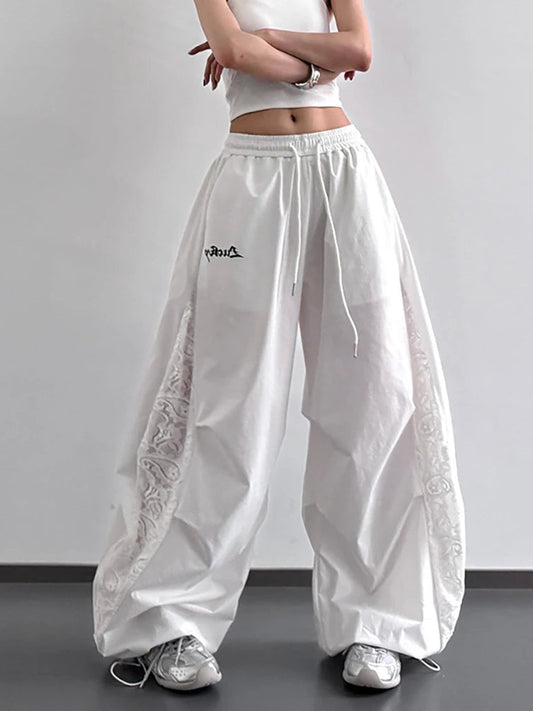 White wide-leg pants with lace details and a brand logo on a plain background